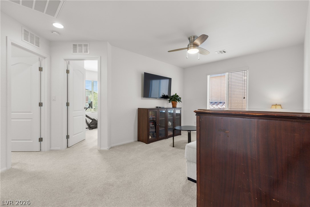 891 Earth Luster Road Las Vegas, NV 89178 - Photo 30 of 48 A versatile bonus room featuring carpeted flooring and a modern ceiling fan, perfect for a home office or relaxation.