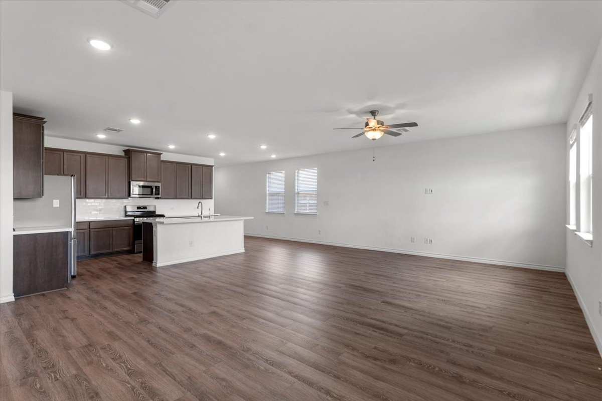 500 Stinchcomb Road Hutto, TX 78634 - Photo 9 of 37 An open concept living area seamlessly blends the kitchen and living space, featuring rich wood flooring throughout.
