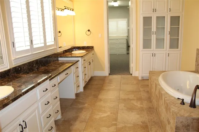 a bathroom with a granite countertop sink and a bathtub