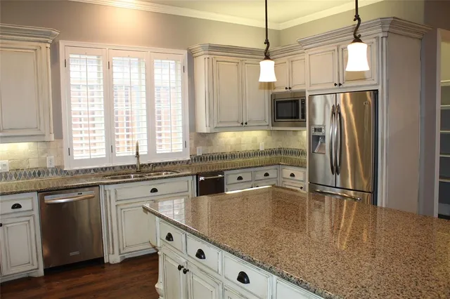 a kitchen with stainless steel appliances granite countertop a sink a stove and a refrigerator