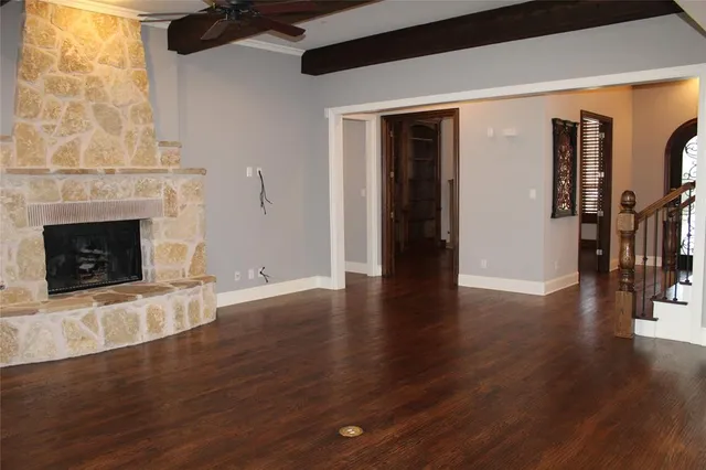 a view of an empty room with wooden floor and a fireplace