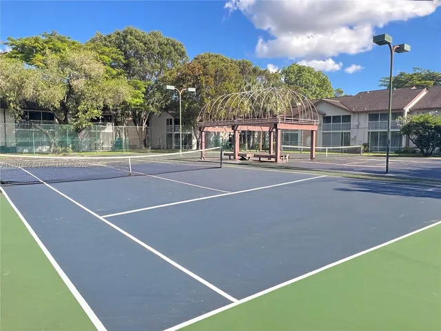 a view of a tennis ground with large trees
