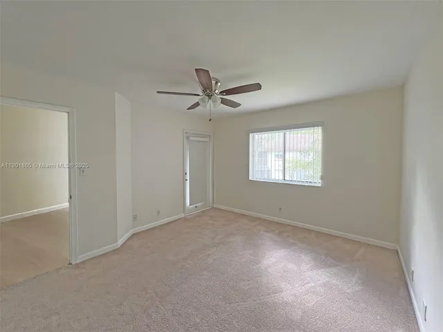an empty room with windows and ceiling fan