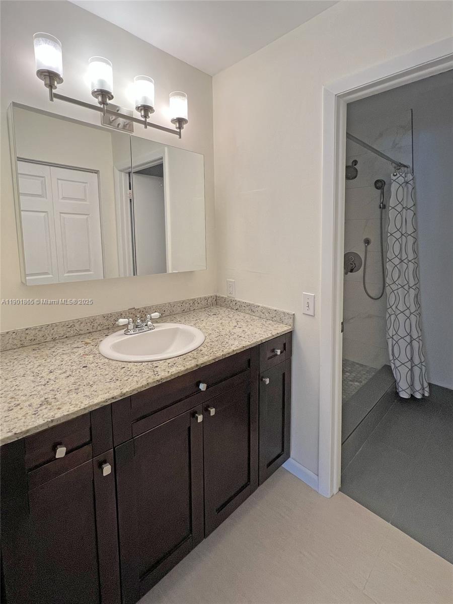 14015 Southwest 91st Terrace, Unit 14015 Miami, FL 33186 - Photo 8 of 20 a bathroom with a granite countertop sink and a mirror