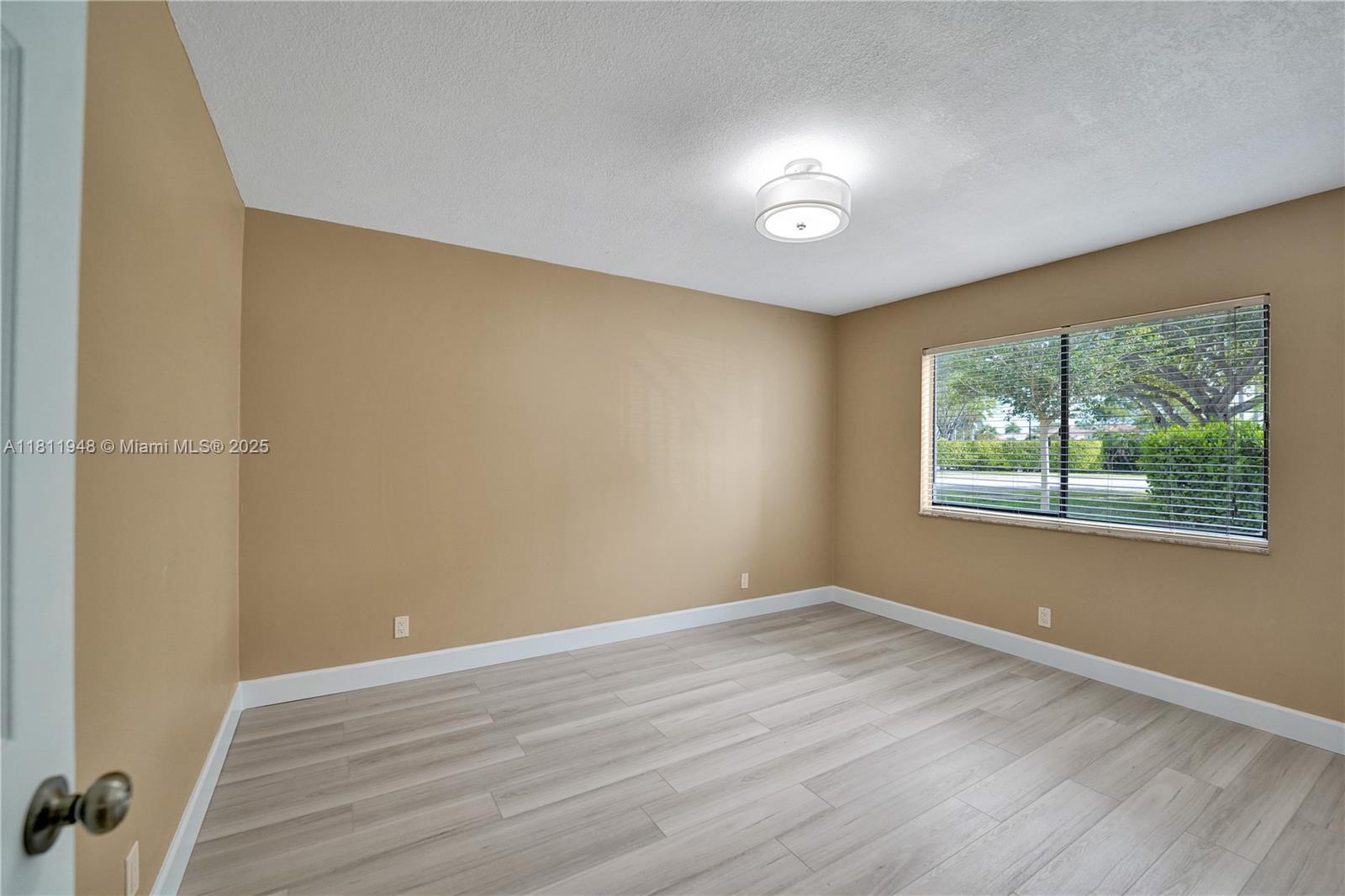 304 Racquet Club Road, Unit 105 Weston, FL 33326 - Photo 23 of 41 a view of an empty room with wooden floor and a window