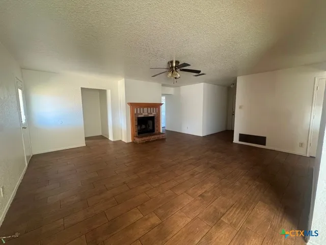 an empty room with wooden floor ceiling fan and windows