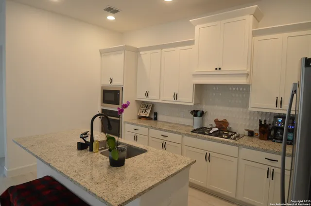 a kitchen with a sink stainless steel appliances and white cabinets