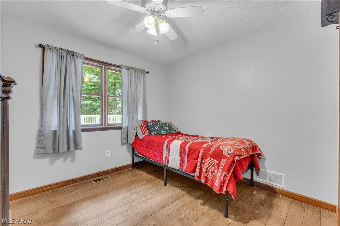 408 River Road Canal Fulton, OH 44614 - Photo 28 of 42 Room featuring wood-finish flooring, a ceiling fan with integrated lighting, and a window with a deck railing visible outside