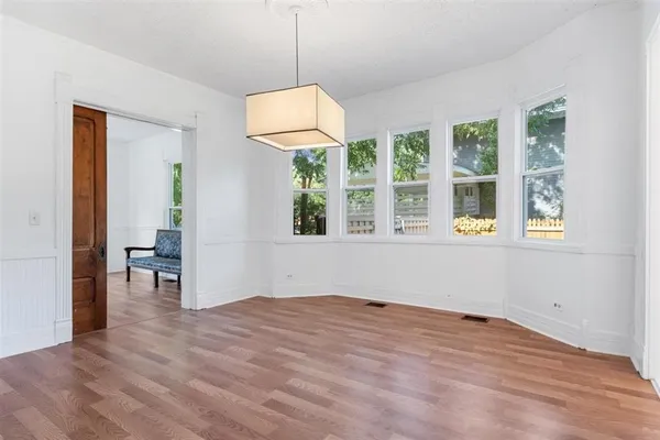 a view of an empty room with a window and wooden floor