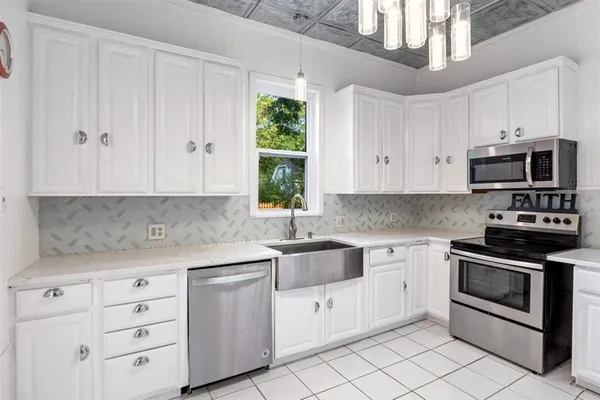 a kitchen with white cabinets appliances and a window