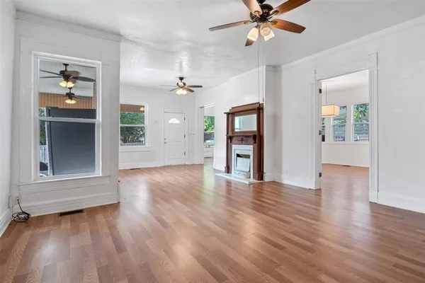 an empty room with wooden floor chandelier and windows