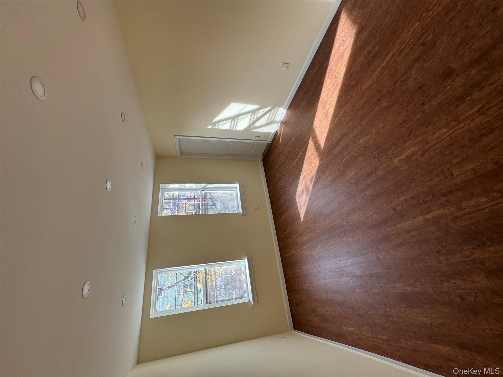 60-03 56th Road, Unit 2 Queens, NY 11378 - Photo 12 of 12 a view of an empty room with wooden floor and a window