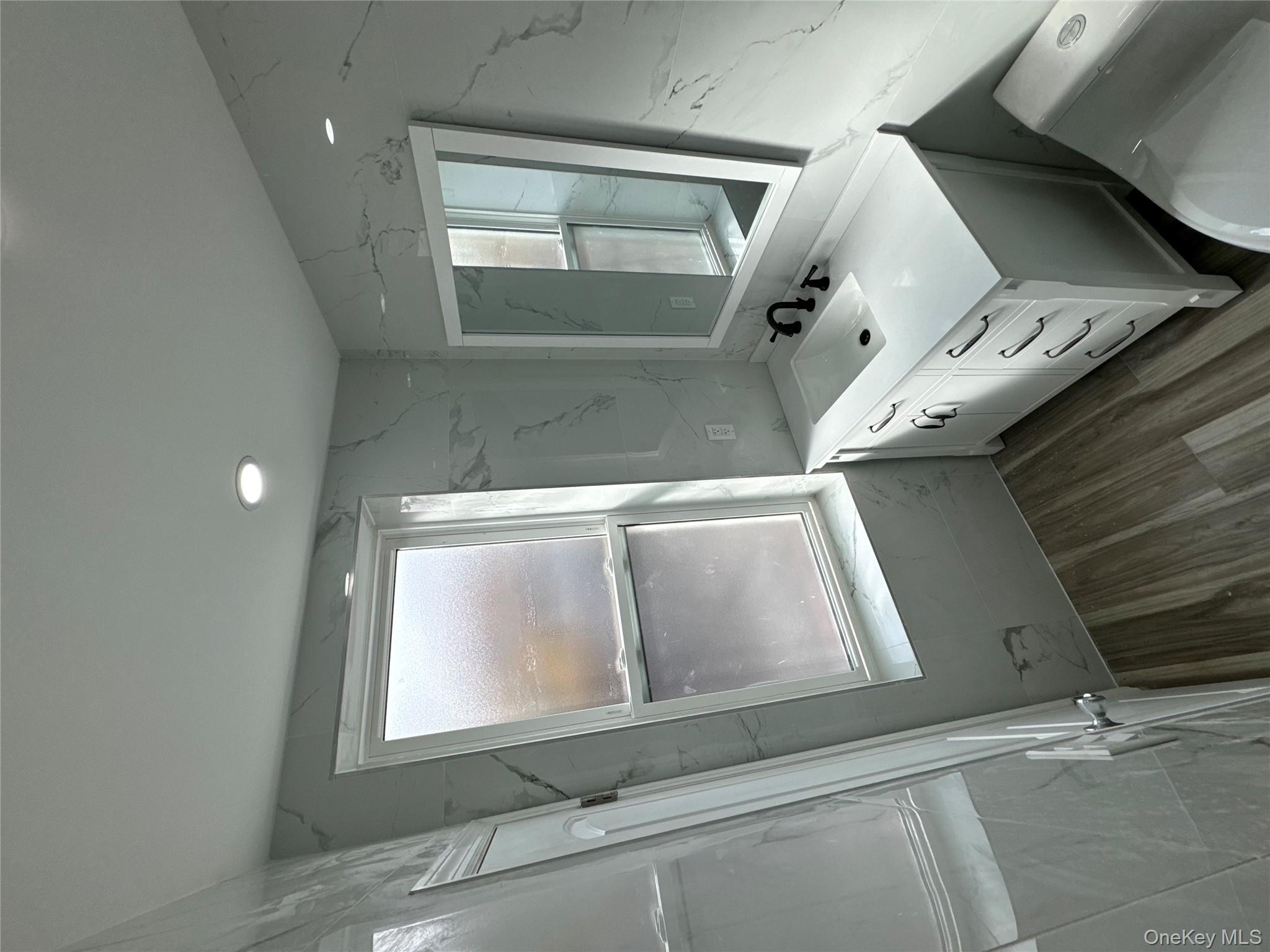 60-03 56th Road, Unit 2 Queens, NY 11378 - Photo 7 of 12 a bathroom with a double vanity sink a mirror and a bathtub