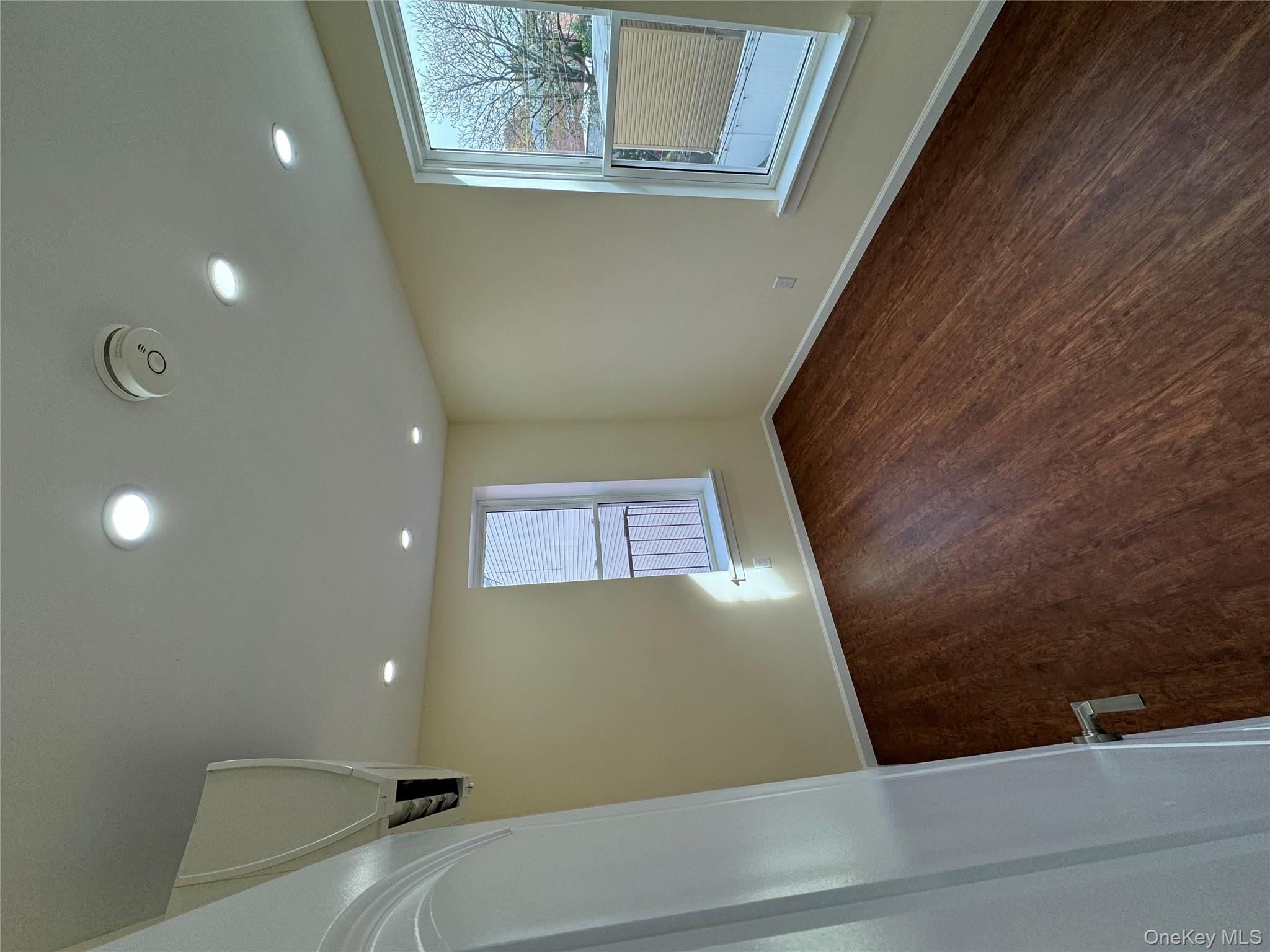 60-03 56th Road, Unit 2 Queens, NY 11378 - Photo 8 of 12 an empty room with wooden floor and windows