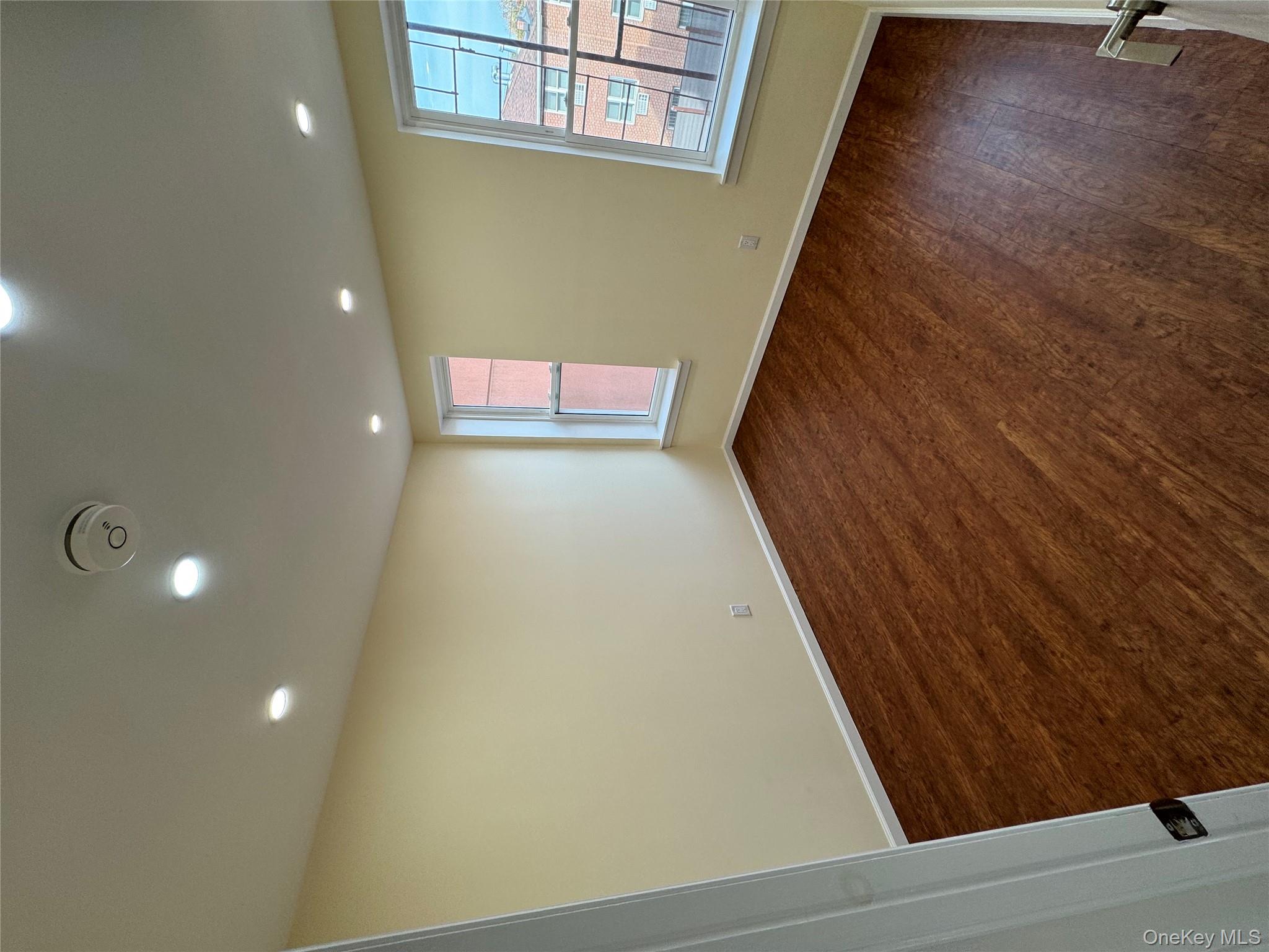 60-03 56th Road, Unit 2 Queens, NY 11378 - Photo 9 of 12 an empty room with wooden floor and windows