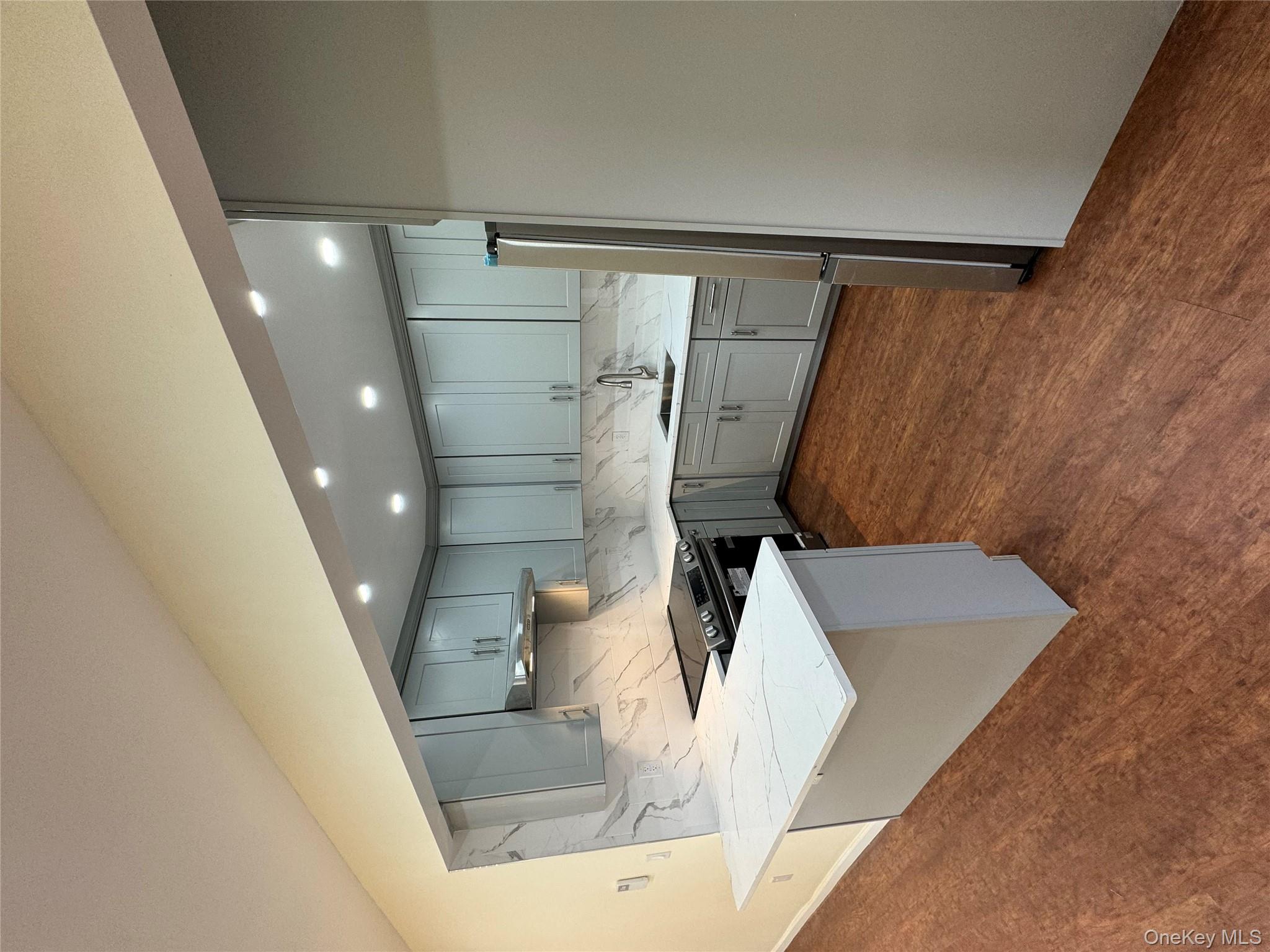 60-03 56th Road, Unit 2 Queens, NY 11378 - Photo 10 of 12 a kitchen with kitchen island a sink stainless steel appliances and cabinets