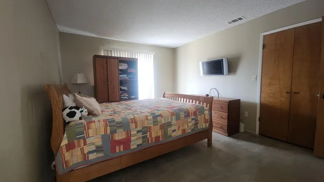 a spacious bedroom with a bed and a tv