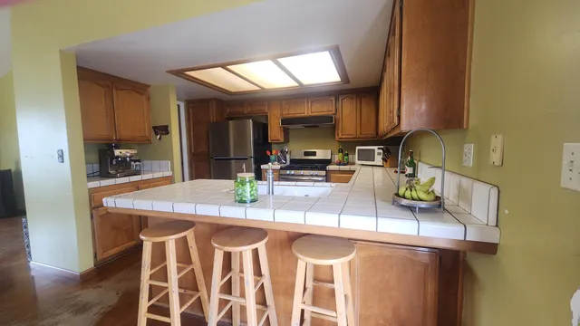 a kitchen with granite countertop kitchen island stainless steel appliances a sink and cabinets