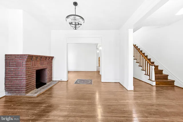 a view of an empty room with wooden floor fireplace and a window