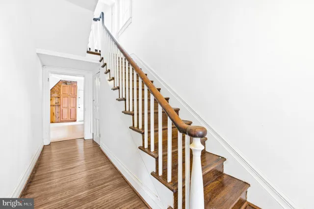 a view of staircase with wooden floor and white walls