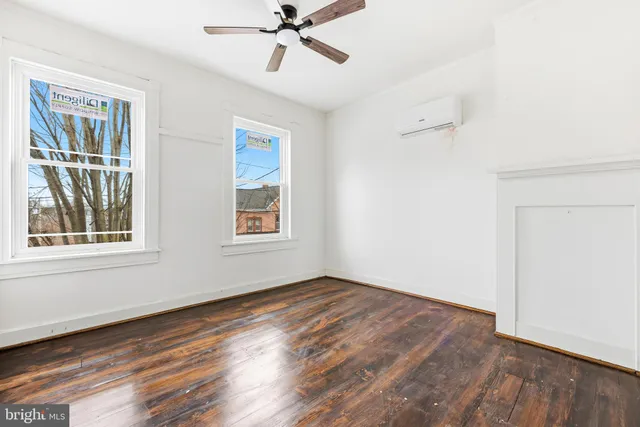 an empty room with wooden floor fan and windows