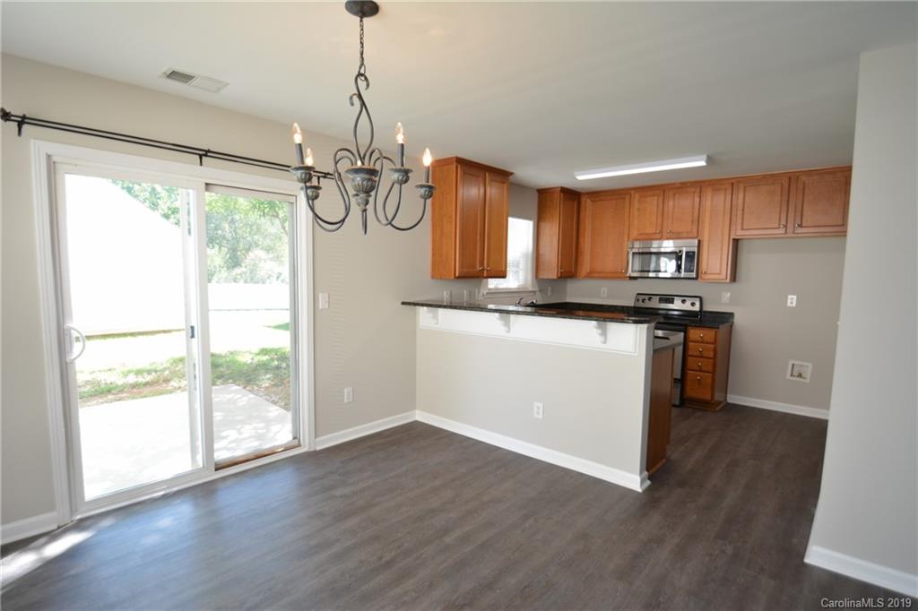 10044 Caldwell Depot Road Cornelius, NC 28031 - Photo 7 of 16 a kitchen with stainless steel appliances granite countertop a refrigerator a sink dishwasher a stove and white cabinets with wooden floor