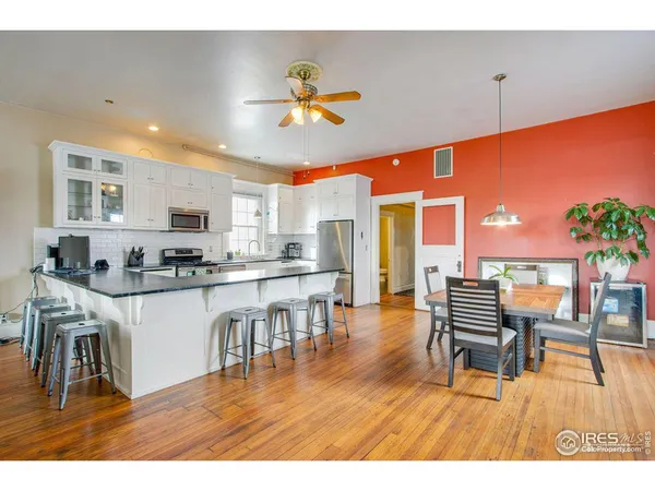 a kitchen with stainless steel appliances kitchen island granite countertop a table chairs and a refrigerator