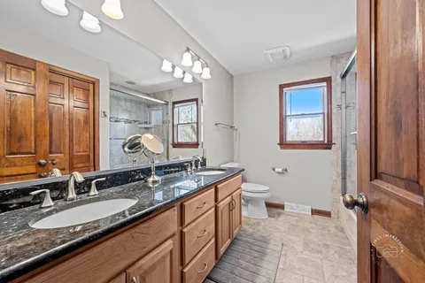 a spacious bathroom with a granite countertop double vanity sink a mirror and a