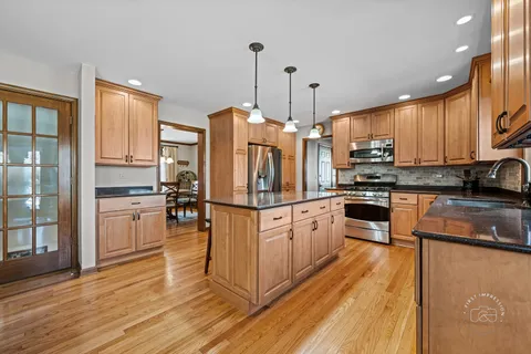 a kitchen with stainless steel appliances granite countertop a refrigerator a stove a sink dishwasher and a oven with wooden floor