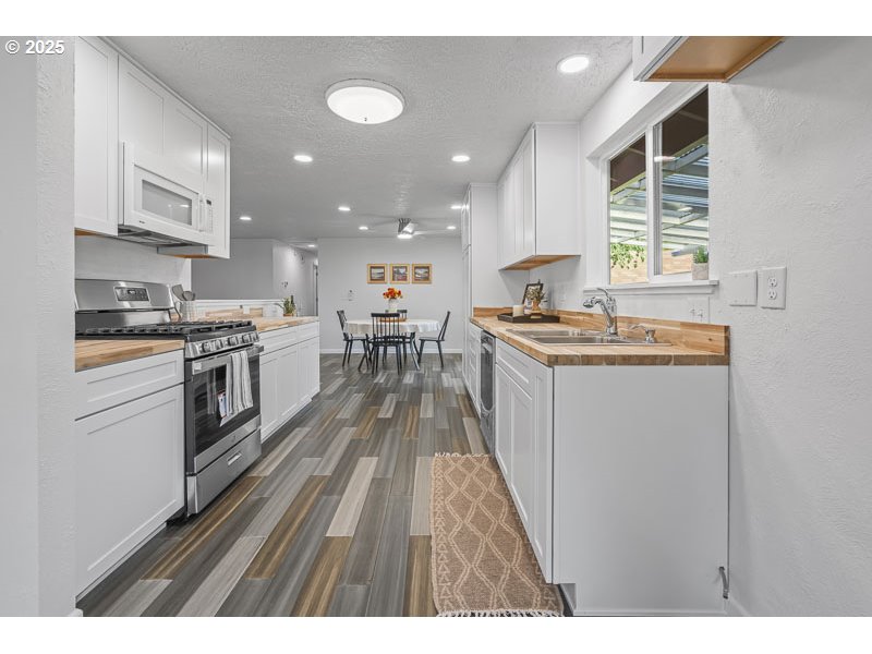 611 Northeast Bockes Loop Sheridan, OR 97378 - Photo 16 of 36 a kitchen with stainless steel appliances granite countertop a stove top oven a sink dishwasher and white cabinets with wooden floor