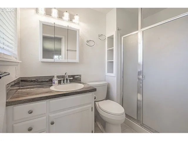 a bathroom with a granite countertop sink mirror vanity and toilet