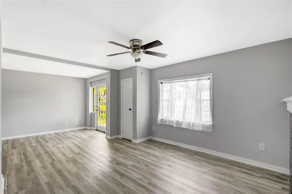 a view of an empty room with window and wooden floor