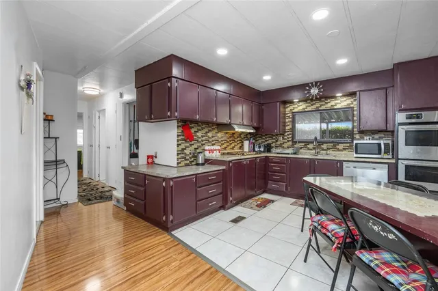 a kitchen with stainless steel appliances kitchen island granite countertop a refrigerator a stove and a wooden cabinets