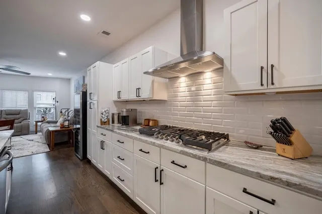 a kitchen with stainless steel appliances granite countertop a refrigerator a stove and white cabinets