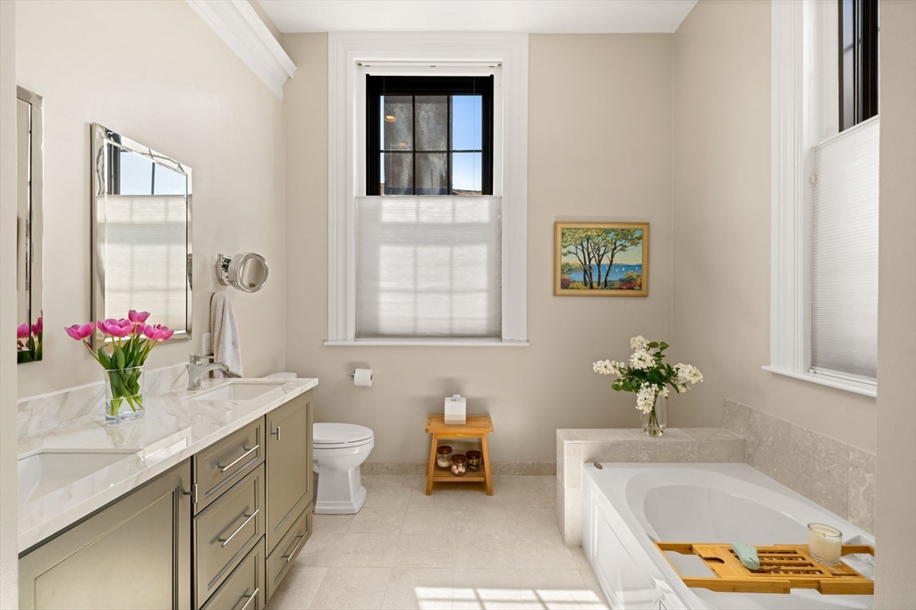 44 Pleasant Street, Unit 1 Marblehead, MA 01945 - Photo 17 of 35 a bathroom with a granite countertop sink a toilet and a mirror