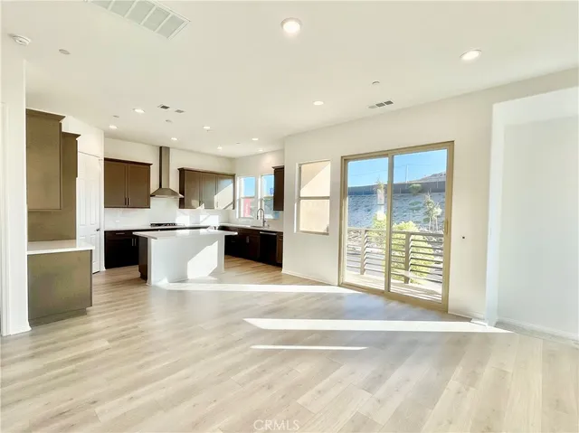 a view of kitchen with kitchen island a sink wooden floor and a refrigerator