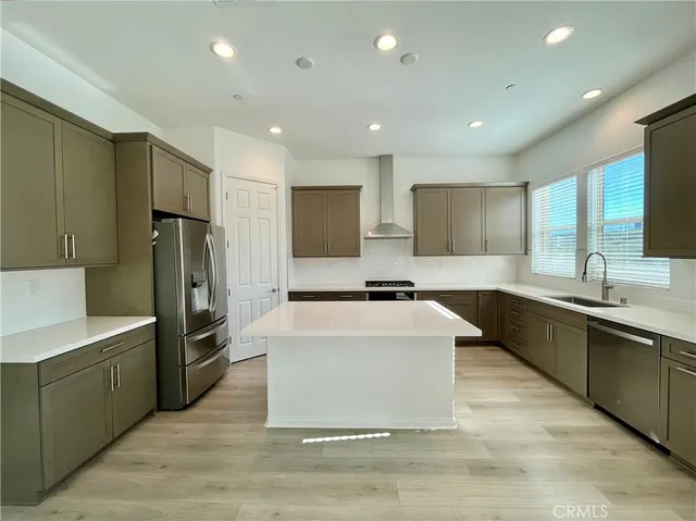 a large kitchen with stainless steel appliances kitchen island granite countertop a large counter top and a refrigerator