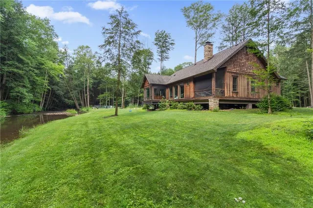 a view of a house with a big yard and large trees