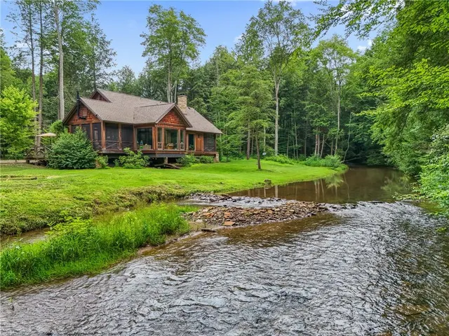 a view of a big house with a big yard and large trees