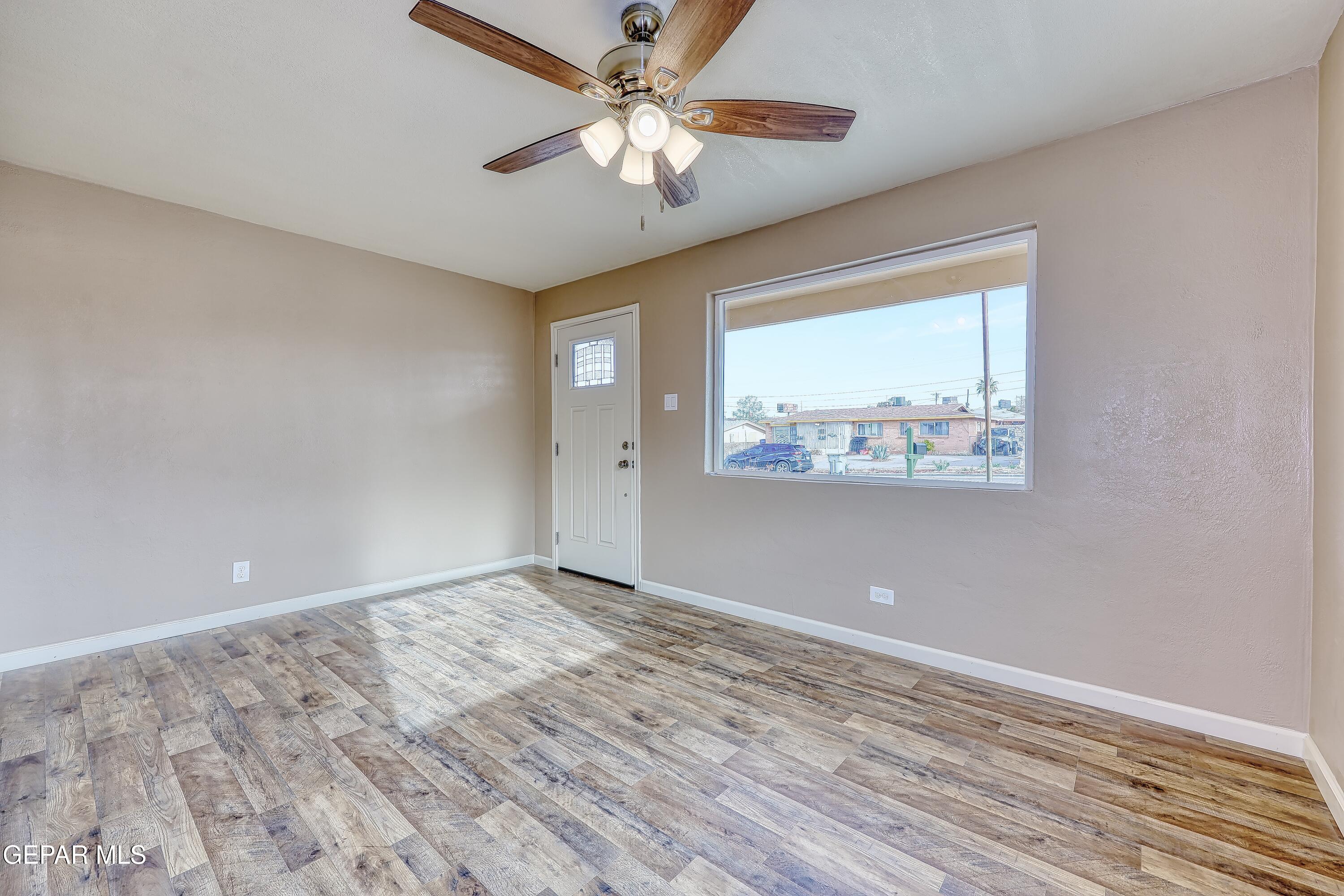 7212 Raton Drive El Paso, TX 79915 - Photo 12 of 44 an empty room with wooden floor chandelier fan and windows