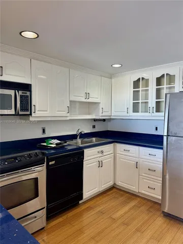 a kitchen with granite countertop cabinets stainless steel appliances and wooden floor