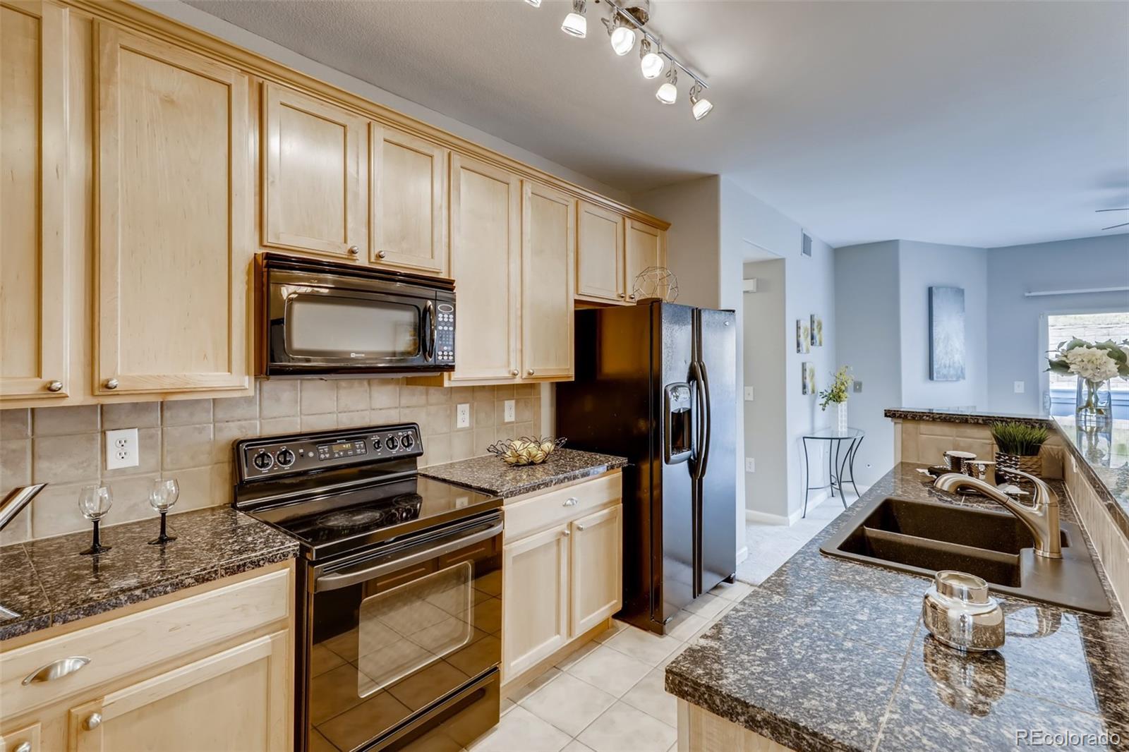 5544 Lewis Street, Unit 203 Arvada, CO 80002 - Photo 13 of 38 a kitchen with a stove a sink and a refrigerator