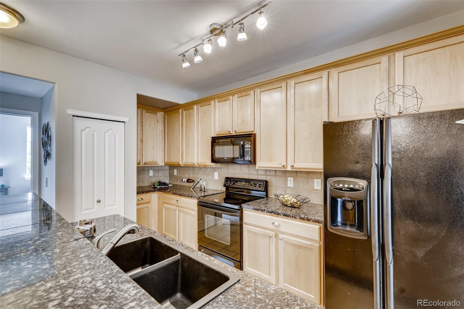 5544 Lewis Street, Unit 203 Arvada, CO 80002 - Photo 10 of 38 a kitchen with a refrigerator a microwave a sink and cabinets