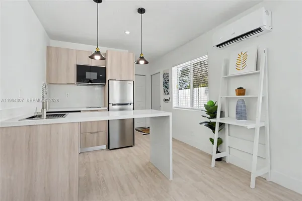 a kitchen with stainless steel appliances granite countertop a sink a stove a refrigerator and white cabinets with wooden floor
