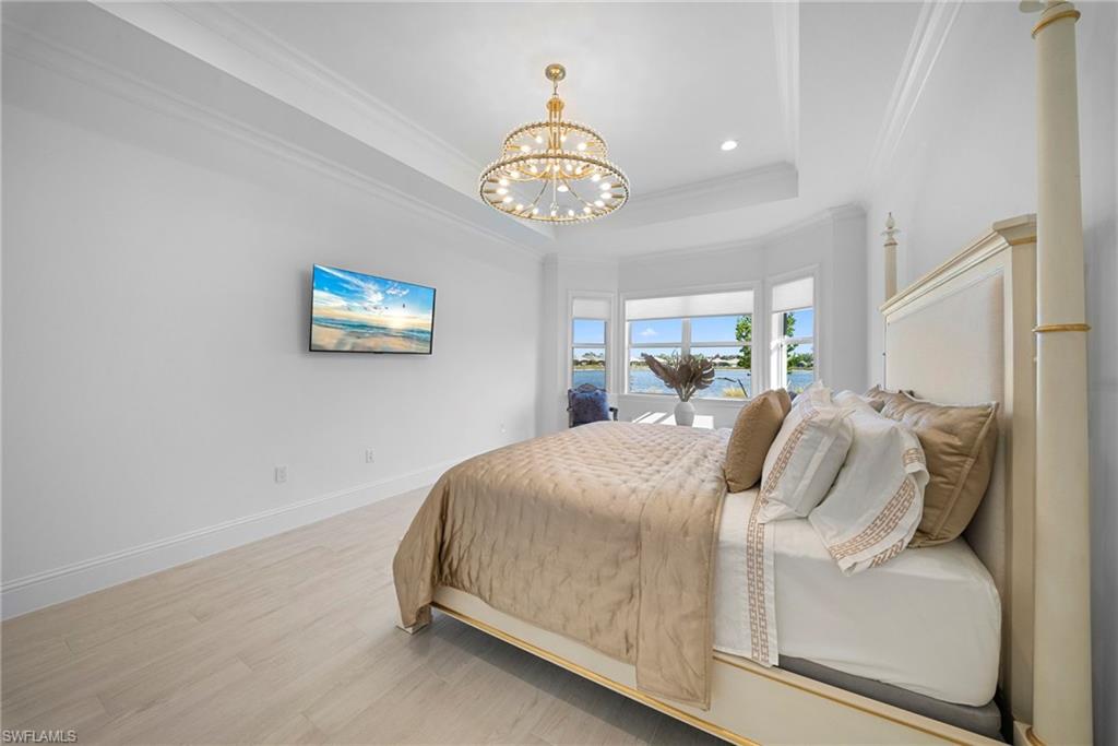 8923 Gustavia Court Naples, FL 34113 - Photo 23 of 50 a bedroom with bed and a chandelier