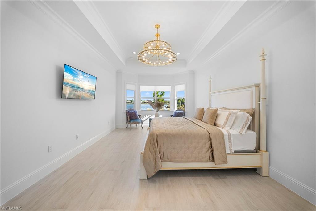 8923 Gustavia Court Naples, FL 34113 - Photo 24 of 50 a bedroom with a bed and a chandelier
