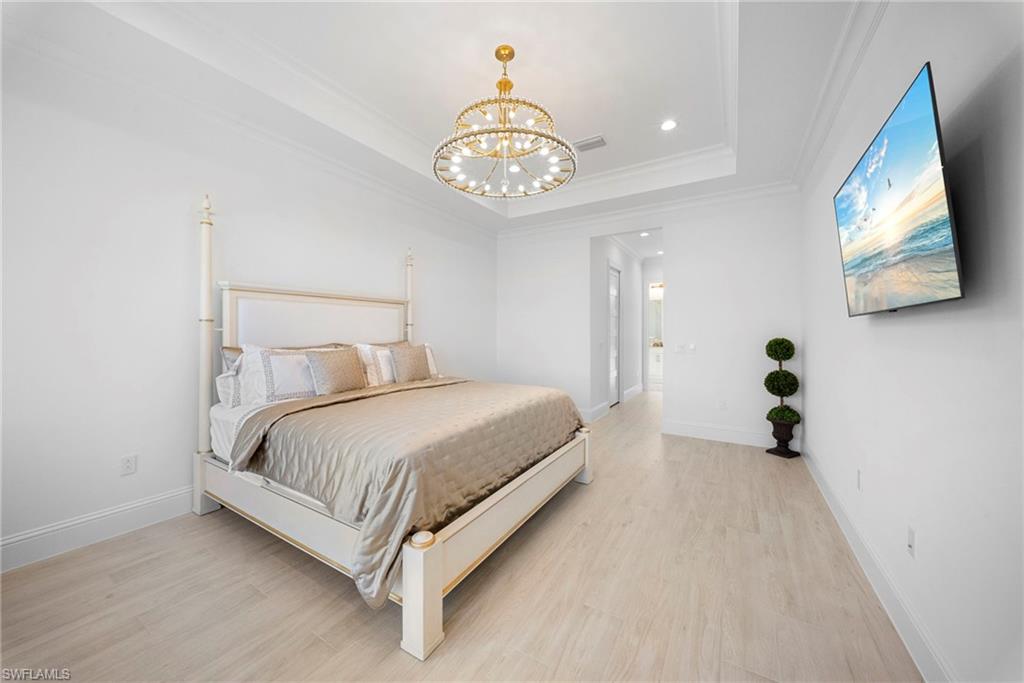 8923 Gustavia Court Naples, FL 34113 - Photo 25 of 50 a bedroom with a bed and a chandelier