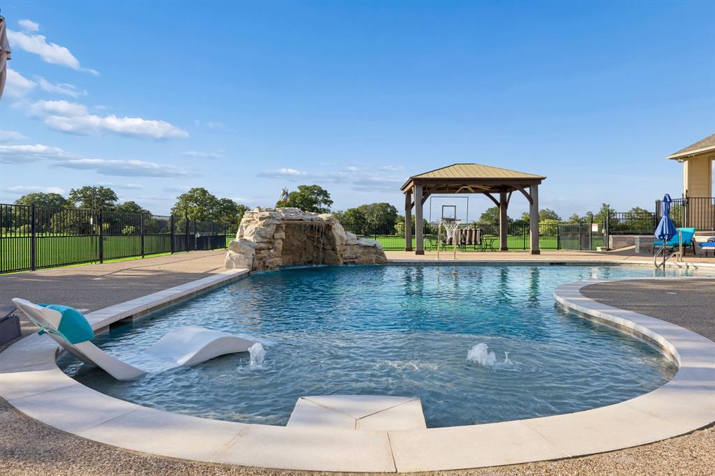 174 King Ranch Court Fort Worth, TX 76108 - Photo 32 of 40 Beat the Texas Heat with your sparkling pool with tanning ledge and stone waterfall.