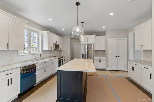 a large kitchen with granite countertop a large kitchen island white cabinetry and stainless steel appliances