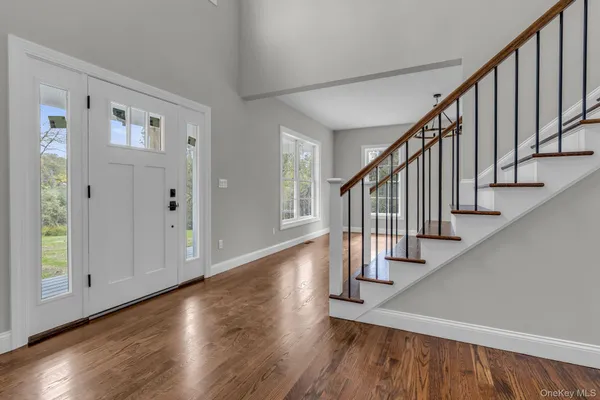 a view of front door with hallway with wooden floor and stairs